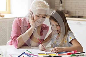 Grandparent and grandchild drawing with color pencils in kitchen