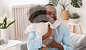 Grandparent grandchild relationship. Senior African American man hugging his granddaughter at home