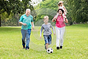 Grandparent And Grandchildren Playing Soccer Ball Together photo