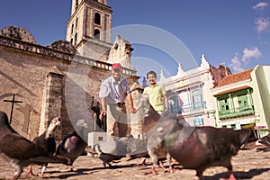 Grandparent And Grandson Feeding Pigeons With Bread On Vacations