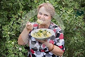 Grandparent woman with boiled potatoes in the plate