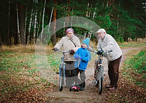 Grandparents on bikes with grandson on schooter ride in nature