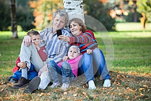 Grandparents with children sitting together and making selfie with cellphone