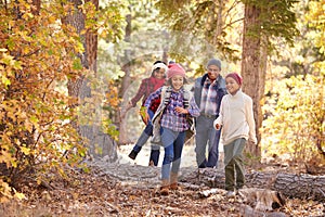 Grandparents With Children Walking Through Fall Woodland