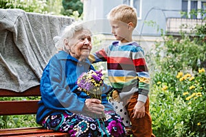 Grandparents Day, Reunited family, togetherness. Senior old grandma hugs grandson outdoors. Grandchild makes surprise