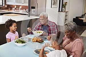 Grandparents Enjoying Meal At Home With Granddaughters