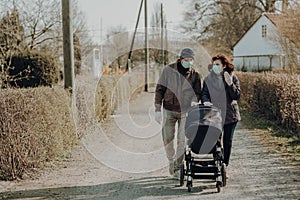 Grandparents in facial masks walking with baby in buggy during quarantine