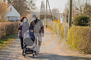Grandparents in facial masks walking with baby in buggy during quarantine