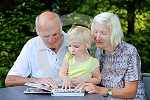 Grandparents with grandchild watching photo album