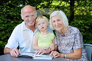 Grandparents with grandchild watching photo album