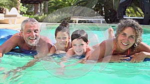 Grandparents With Grandchildren On Airbed In Swimming Pool