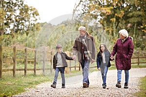 Grandparents With Grandchildren On Autumn Walk In Countryside Together