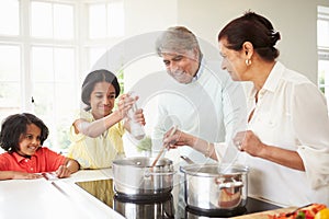 Grandparents And Grandchildren Cooking Meal At Home