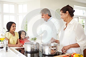 Grandparents And Grandchildren Cooking Meal At Home