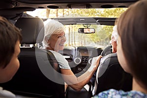 Grandparents And Grandchildren Driving In Open Top Car
