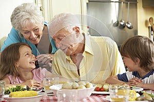 Grandparents And Grandchildren Eating Meal Together In Kitchen