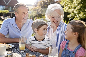 Grandparents With Grandchildren Enjoying Outdoor Summer Snack At Cafe photo