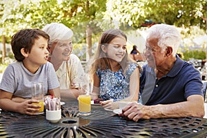 Grandparents And Grandchildren Enjoying Snack At Outdoor Cafï¿½