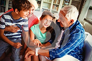 Grandparents and grandchildren looking at smartwatch in living room