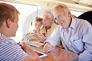 Grandparents And Grandchildren Relaxing On Train Journey