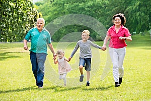 Grandparents And Grandchildren Running In Park