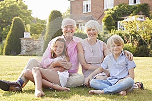 Grandparents and grandchildren sitting on grass in a garden