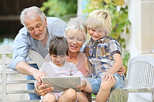 Grandparents and grandchildren using tablet photo