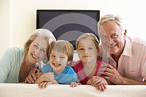 Grandparents And Grandchildren Watching Widescreen TV At Home