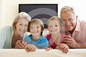 Grandparents And Grandchildren Watching Widescreen TV At Home