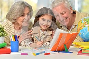 Grandparents with granddaughter drawing on the table