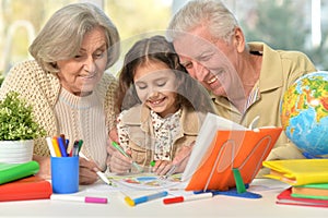 Grandparents with granddaughter drawing on the table