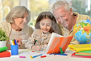 Grandparents with granddaughter drawing on the table