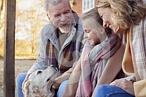 Grandparents With Granddaughter And Pet Dog Outside House Getting Ready To Go For Winter Walk