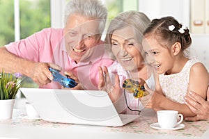 Grandparents with granddaughter playing computer game