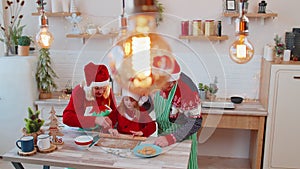 Grandparents with granddaughter preparing, cooking homemade cookie roll out dough, Christmas kitchen