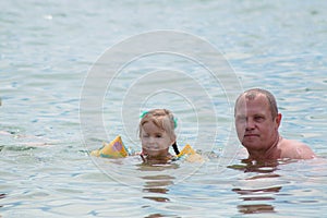 Grandparents And Granddaughter swimming in the sea, they smile and happyness