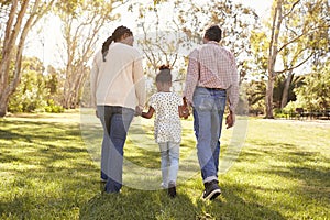 Grandparents And Granddaughter Walking In Park Together