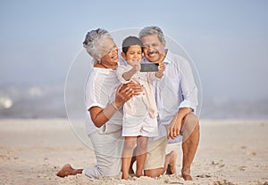 Grandparents with grandson at the beach holding mobile and taking selfie or doing video call with family during vacation