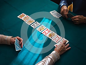 Grandparents hands playing card game in home