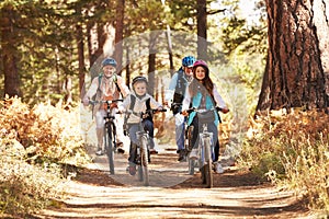 Grandparents and kids cycling on forest trail, California