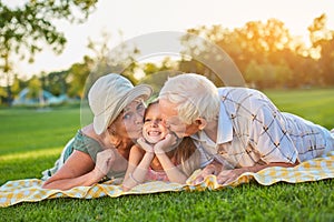 Grandparents kissing happy granddaughter.