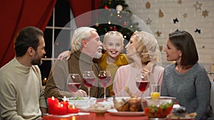 Grandparents kissing little girl, big family having Xmas dinner, happy time