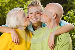 Grandparents kissing their granddaughter