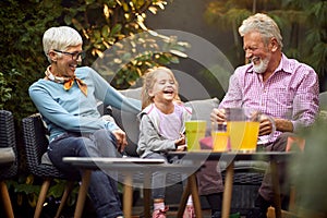 Grandparents laughing out loud with their granddaughter, having wonderful time photo