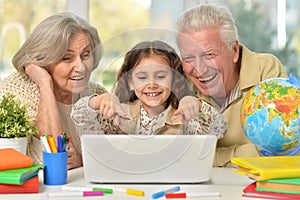 grandparents and little girl using laptop on the table