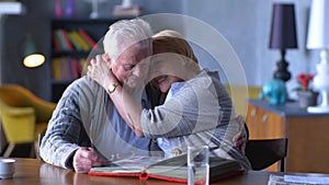 Grandparents looking old photo album and hugging