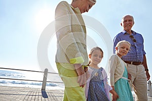 Grandparents make childhood special. grandparents walking hand in hand with their granddaughters on a promanade.