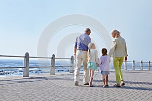 Grandparents make every day spacial. grandparents walking hand in hand with their granddaughters on a promanade.