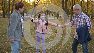 Grandparents are playing and having fun in autumn Park with her granddaughter.