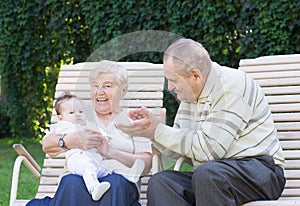 Grandparents playing with a little baby in the garden